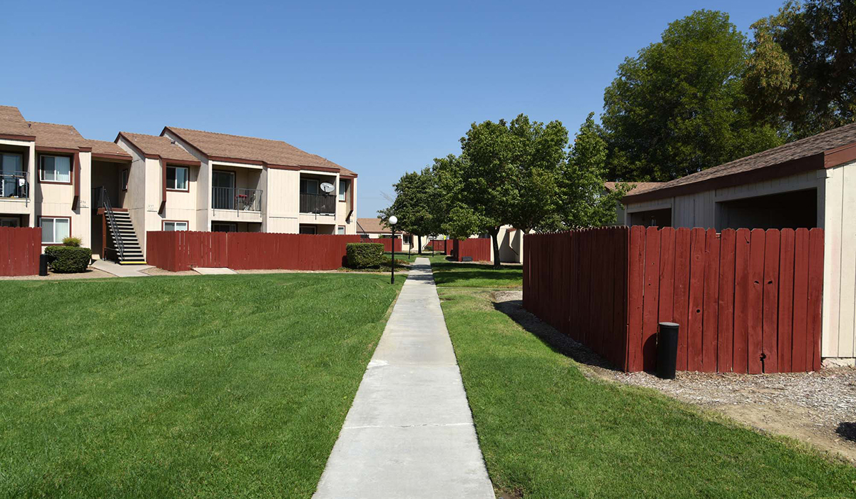 Path running through apartment complex with trees and grass